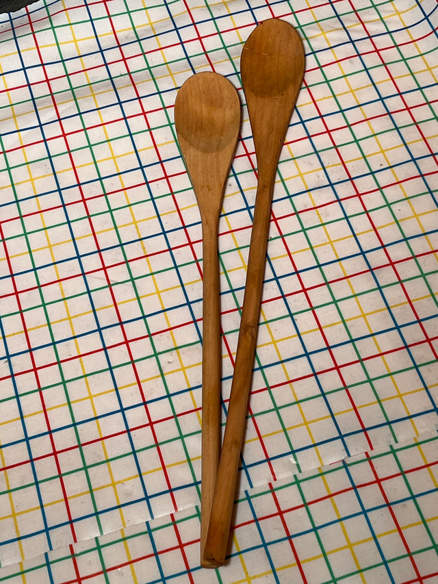 Basic wooden spoon pair on a patterned cloth, showcasing long, flat designs ideal for non-stick cooking, with heat-resistant handles for safe, everyday use.
