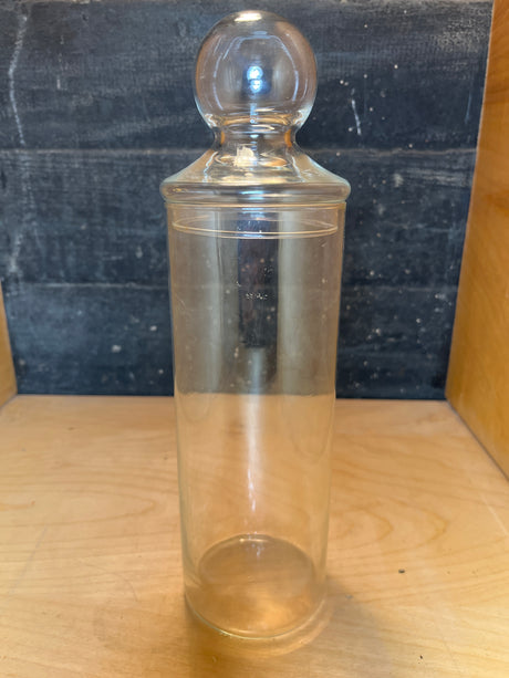 Libbey tall apothecary jar with a lid, featuring a cylindrical design and round knob, displayed on a wooden surface.