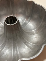 Northland Aluminum Products Inc., Original Bundt Cake pan (vintage Nordic Ware) features a fluted aluminum design with scalloped edges and a central hollow column, ideal for baking.
