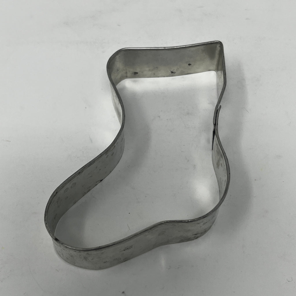 Mid century metal cookie cutter in boot shape on white surface.