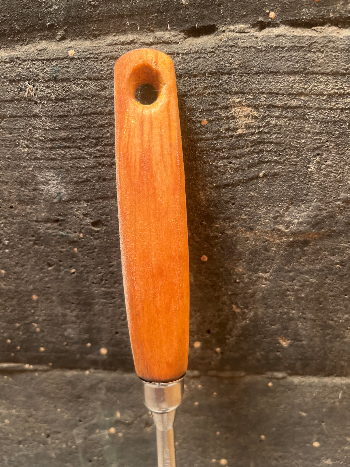 Stainless steel ladle with wood handle - EKCO Eterna, showcasing a metal ferrule and orange-stained handle, ideal for easy scooping with its wide base.