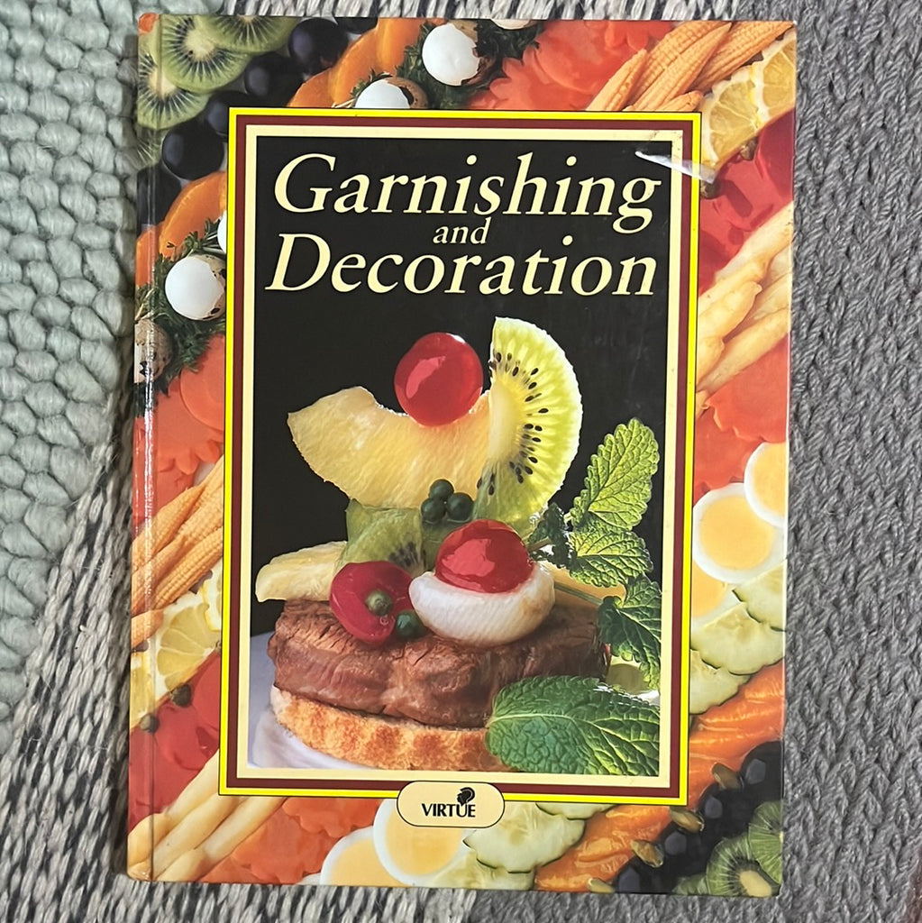 A cookbook titled "Garnishing and Decoration" by Virtue & Company Limited with a colorful cover featuring an assortment of fruits, spoons, and a decorated dish.