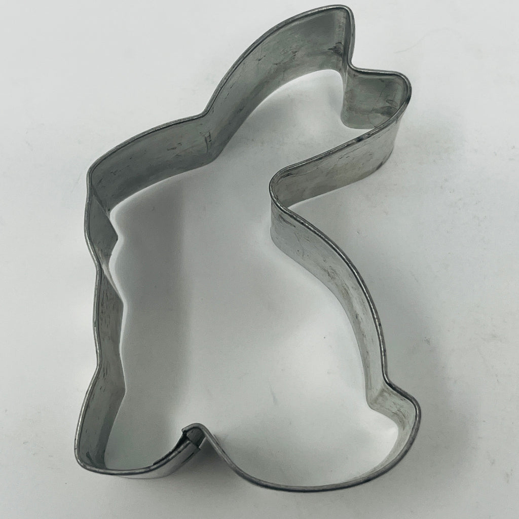 Mid century metal cookie cutter in rabbit shape with curved edge on white surface.