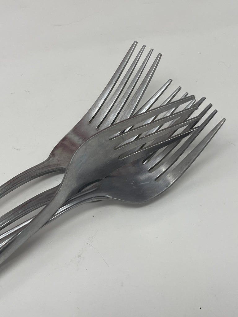 Basic metal cutlery on a white surface, showcasing a close-up of forks, part of the steel eating utensil collection sold individually for precise quantity selection.