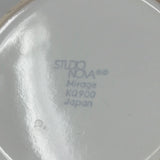 Studio Nova ceramic dish with lid, a white plate with black text, a close-up of a logo, and circular objects in the sky.