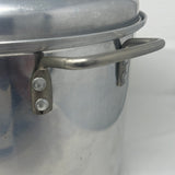 Close-up of Century Ware stock pot with steamer basket, showcasing metal handle and surface. Kitchenware ideal for cooking and baking.