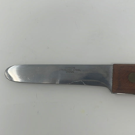 Stainless steel Japanese oyster shucking knife with wood handle, featuring initials of previous owner. Close-up view of knife on wooden surface.