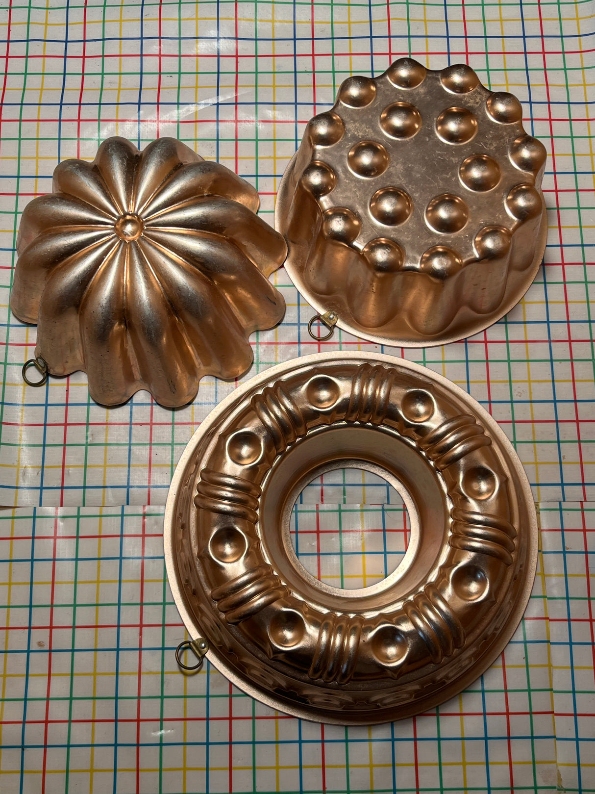 Copper-lined aluminum molds for jello featuring a round ring and two domed designs with hanging loops, ideal for crafting elegant desserts.