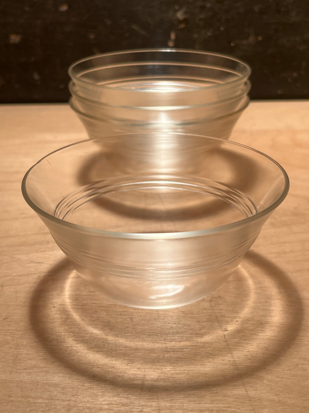 Ramekins/custard cups - PYREX 445 set of 4, showcasing two clear bowls with horizontal bands, casting circular reflections on a wooden surface.