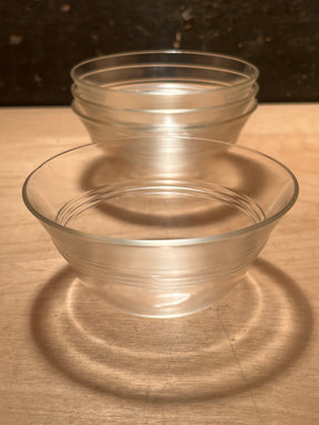 Ramekins/custard cups - PYREX 445 set of 4, showcasing two clear bowls with horizontal bands, casting circular reflections on a wooden surface.