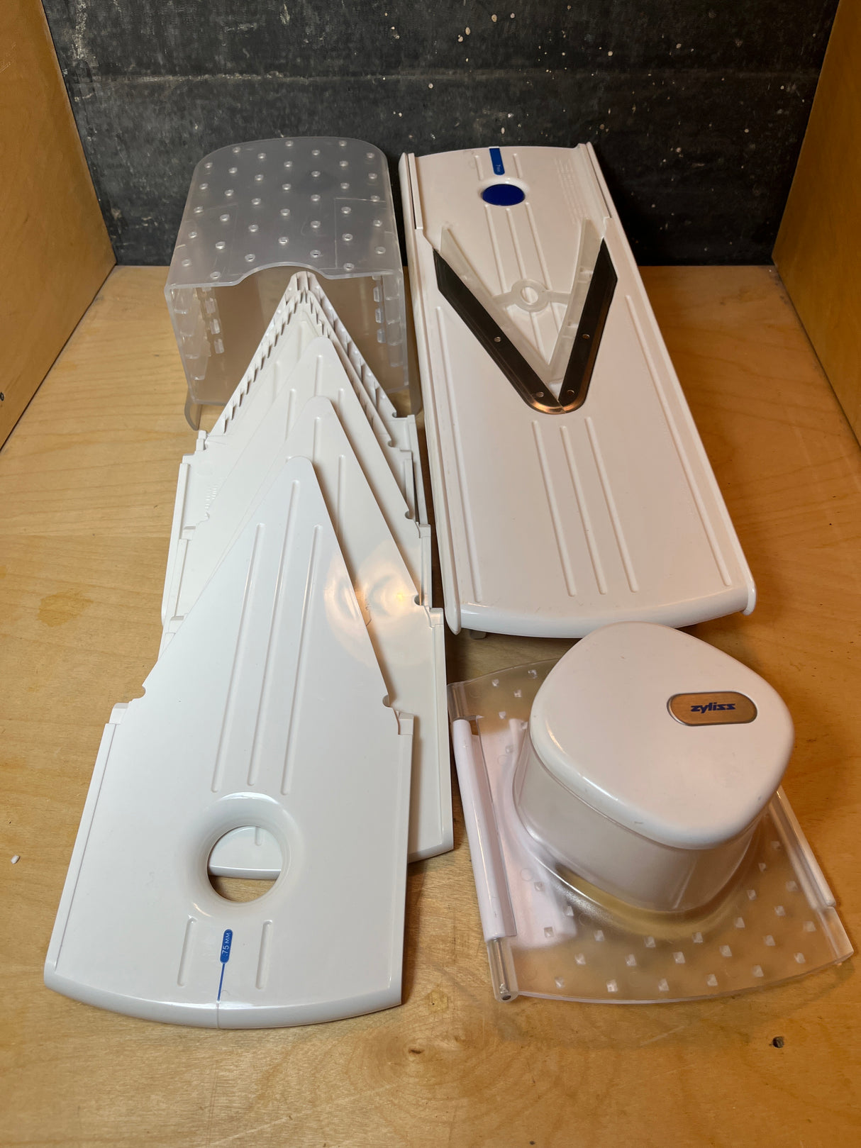 Zyliss Easy Slice mandolin, featuring a V-shaped stainless blade, interchangeable thickness inserts, a clear base tray, and a food pusher for safe slicing.