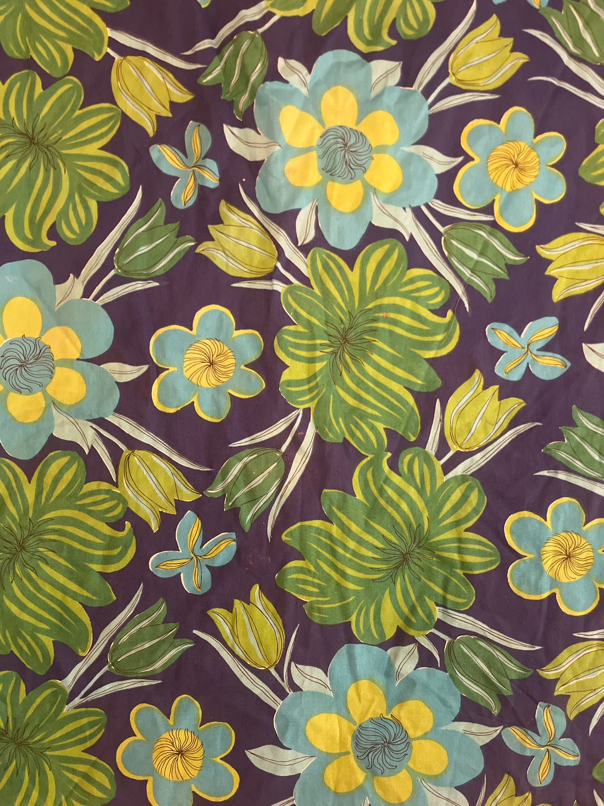 Vintage tablecloth featuring a bold, folk-art floral pattern with stylized flowers and leaves on a deep purple background.