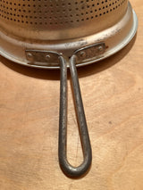 Cone sieve strainer with wide base - aluminum, featuring a riveted base and U-shaped handle, ideal for canning and preserving, displayed upside-down on wood.