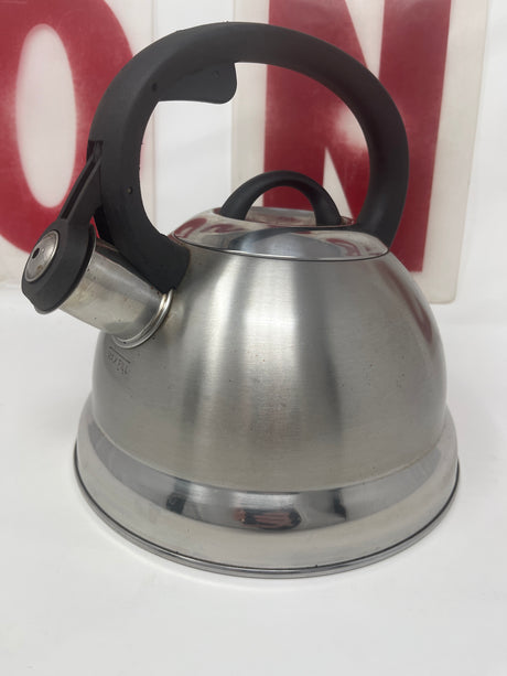 Mr. Coffee stainless steel 1.75-quart tea kettle with black handle, featuring a whistle, in good condition with minor surface wear.