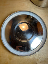Bottom side of a stainless steel food storage container with a removable white silicone anti-skid ring, showcasing concentric rings on a wooden surface.