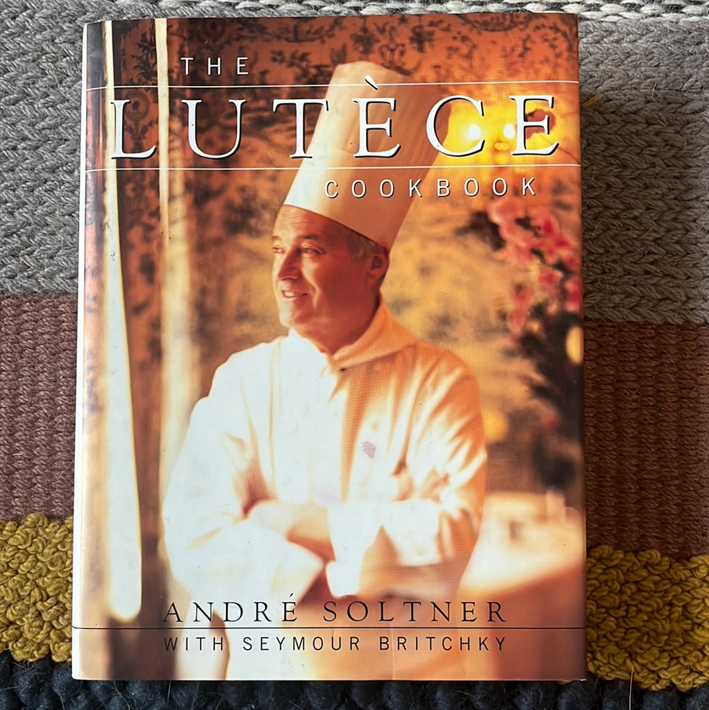 A cookbook featuring classic French cuisine recipes: The Lutéce Cookbook, with detailed instructions and personal anecdotes. Front cover features photo of André Soltner in chef's uniform. From Spoons Kitchen Exchange.
