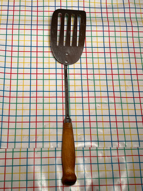 Flat thin steel slotted spatula with wood handle - vintage, shown lying flat, features a long handle, thin edge, and slots for easy flipping and grilling.