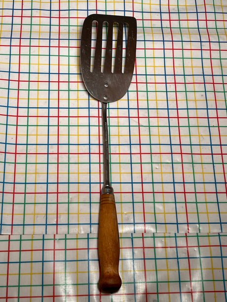 Flat thin steel slotted spatula with wood handle - vintage, shown lying flat, features a long handle, thin edge, and slots for easy flipping and grilling.