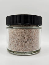 Kala Namak Indian Salt in a clear jar with black lid, showcasing its pinkish-gray granules, known for its egg-like flavor, ideal for vegan cooking.