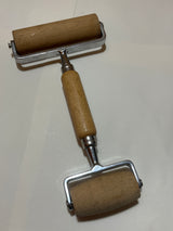 Pampered Chef double rolling pin for pizza and dough features a two-sided wooden cylinder design, metal frame, and central wooden handle, ideal for printmaking and crafts.