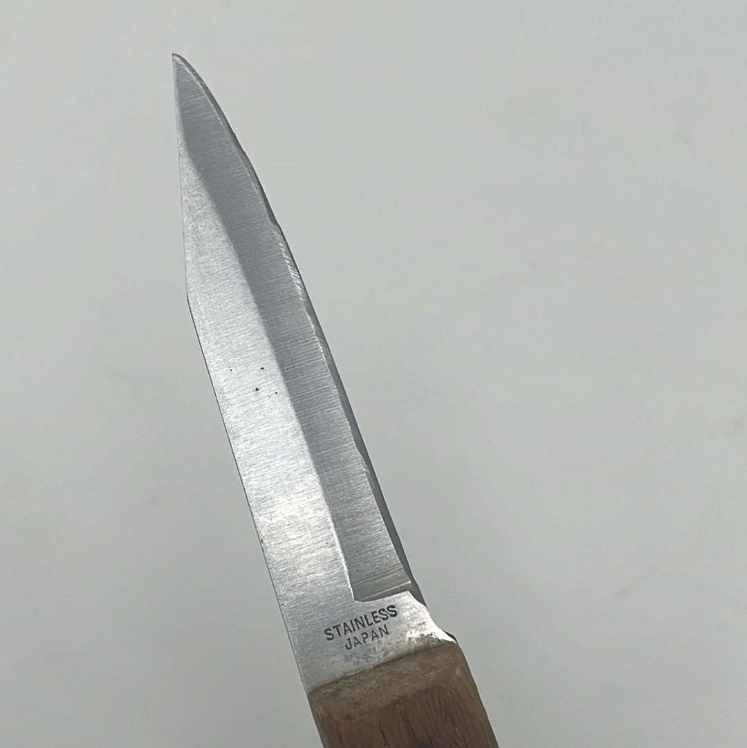 A close-up of the Old Homestead parer knife with a thick, razor-thin blade and a wooden handle, ideal for precise cutting tasks.