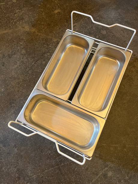 Set of 3 stainless steel steam pans in a white wire rack, ideal for kitchen prep or buffet use, no lids included.