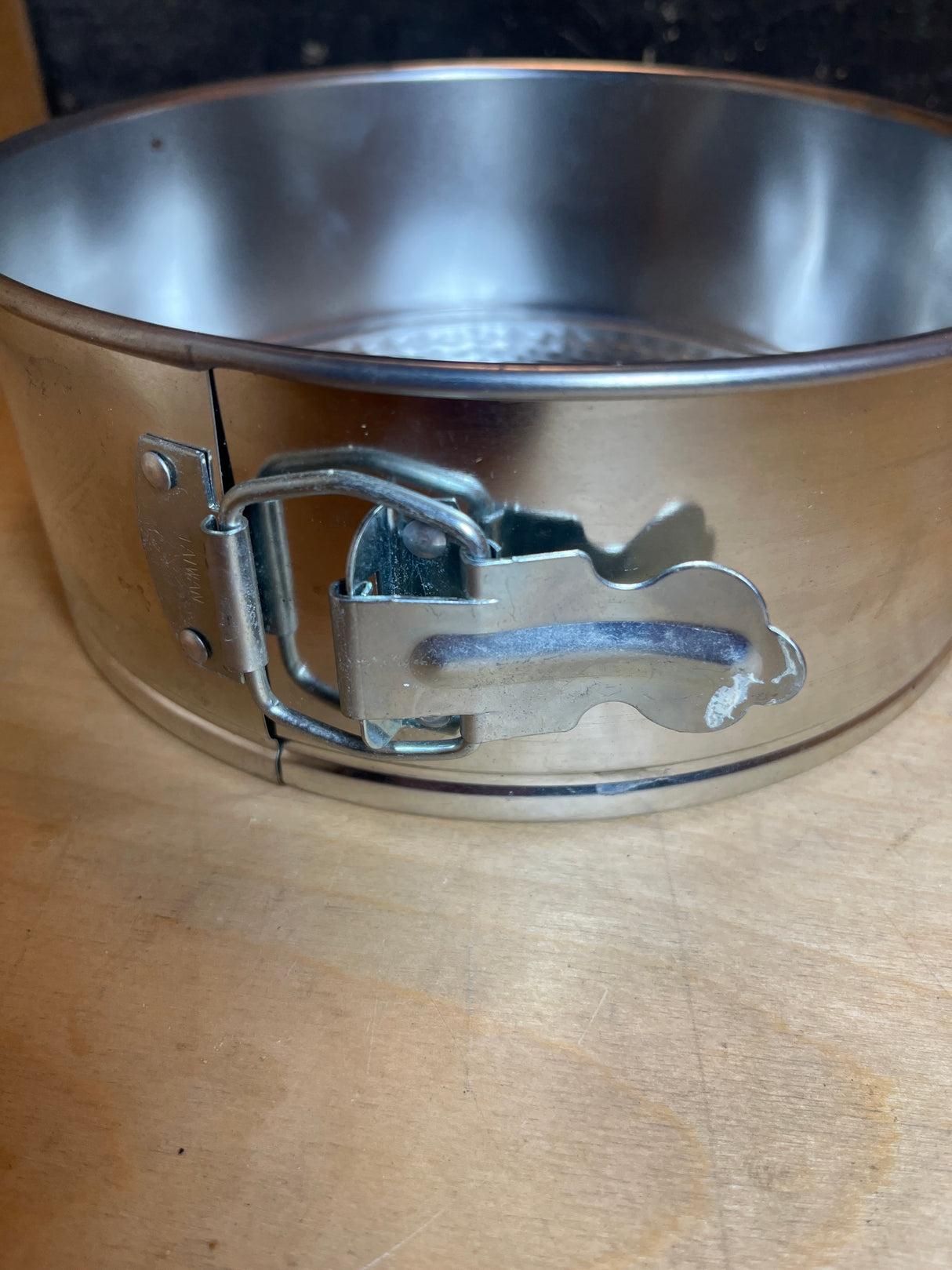 Close-up of the latch mechanism on the Springform cake pan - light tin, 8” diameter, highlighting its removable bottom and adjustable sides for easy cake release.