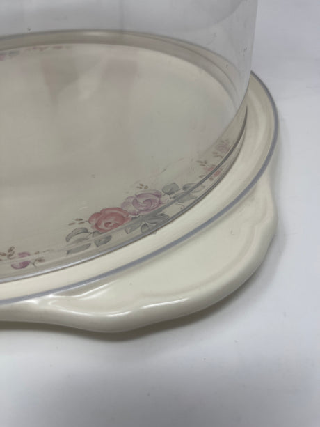 Pfaltzgraff rose motif cake plate with cover, featuring a glass dome adorned with a flower design and small handles for easy carrying.