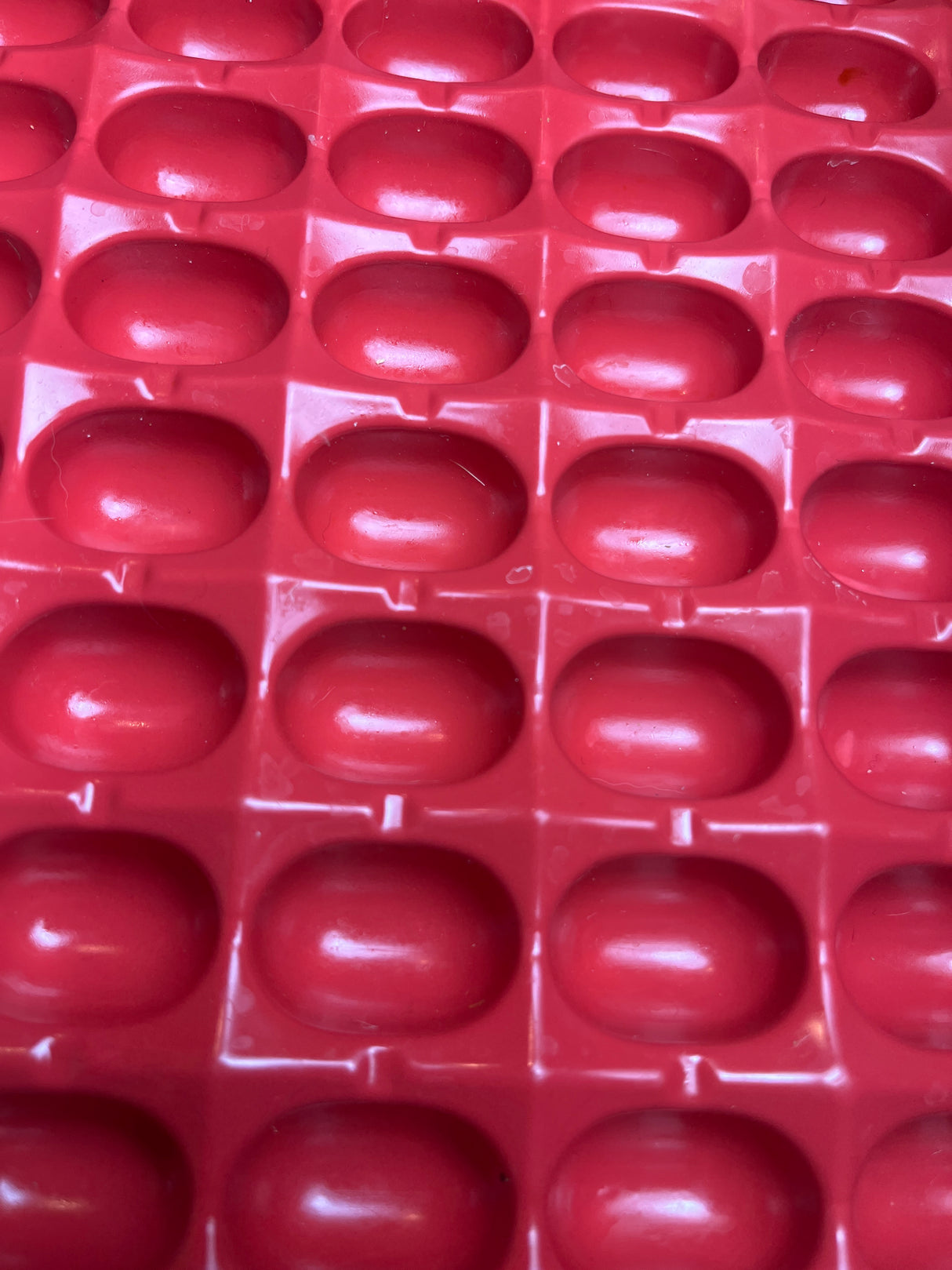 Jell-O Jiggler vintage mold in red plastic, featuring a grid of small, oval-shaped wells, designed to create 82 jelly shots or bean-shaped treats.