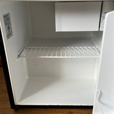 GE Spacemaker Compact Refrigerator with Freezer, featuring a small freezer section, removable wire rack, and slight dent on one corner, enhancing its compact functionality.