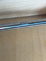 Close-up of Pedrini stainless steel slotted serving spoon, showcasing the “INOX” stamp, resting on a wooden surface, highlighting its durable stainless steel construction.