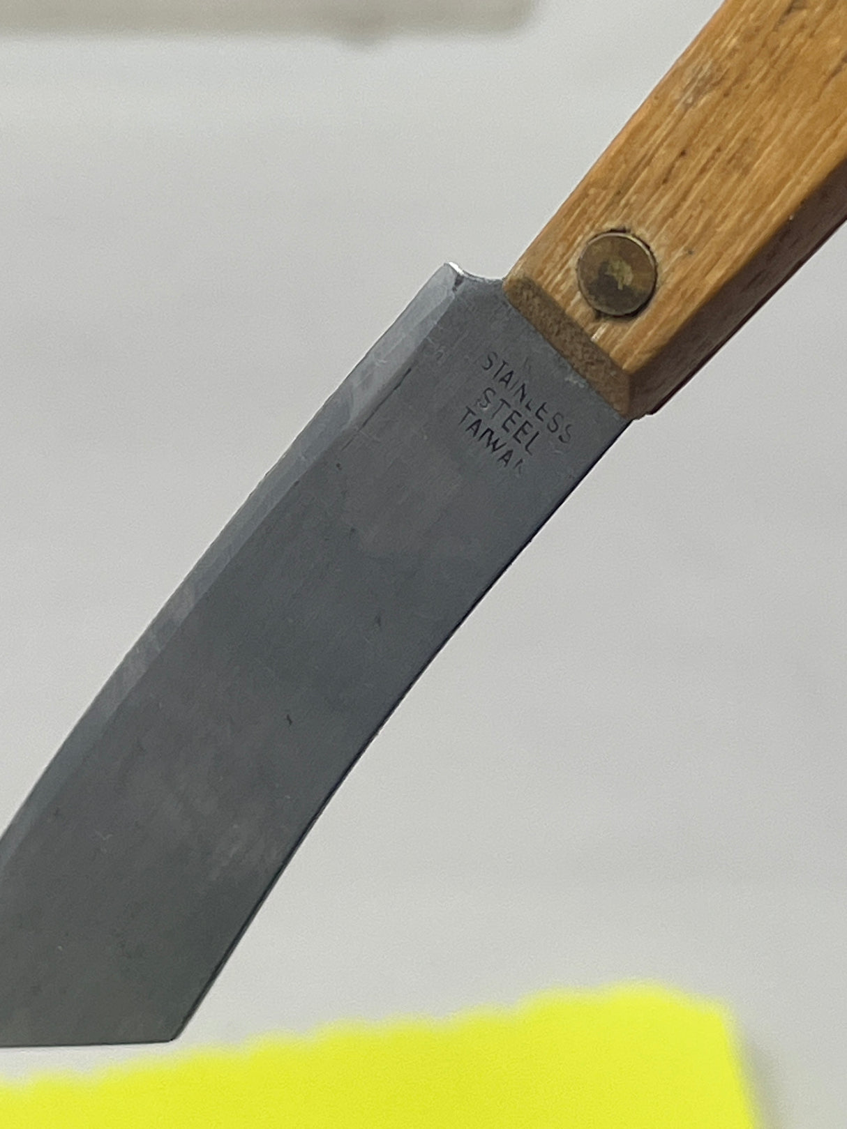 Little stainless utility knife with wood handle, featuring a compact, cleaver-like shape, ideal for precise kitchen tasks like slicing herbs and chilis.