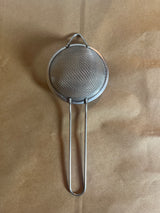 Stainless steel mesh strainer with loop handle, 2.5 inch, ideal for steeping tea or sifting powders, features a long handle and hanging ear for convenience.