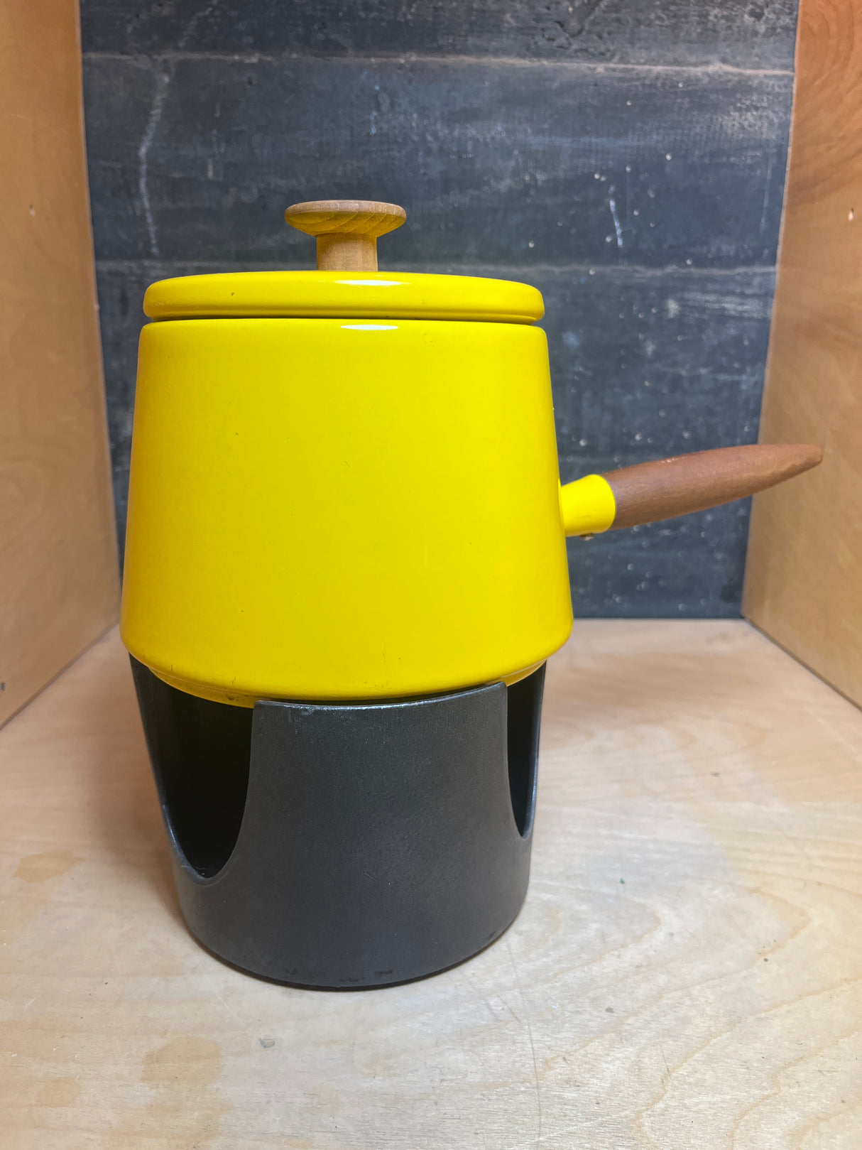 Fondue pot - vintage Michael Lax Copco - yellow enamel, featuring a wooden knob, side handle, and black warming stand. Note: missing burner cover and enamel chip.