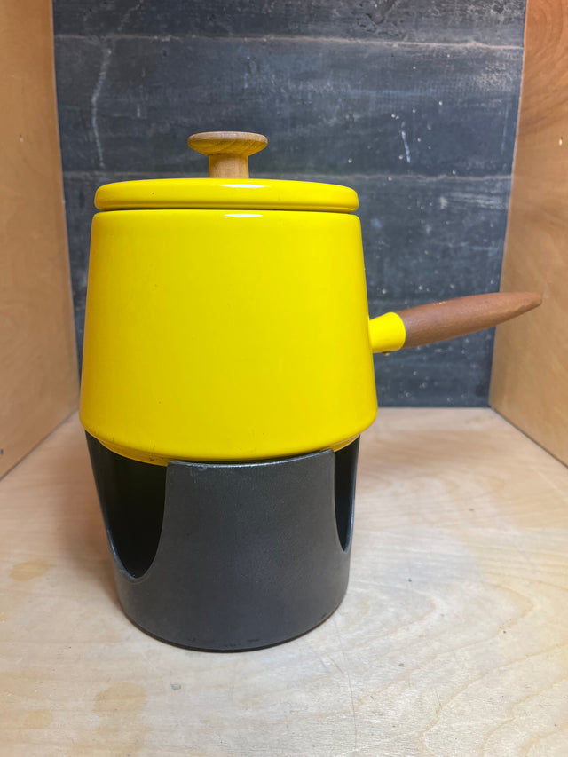 Fondue pot - vintage Michael Lax Copco - yellow enamel, featuring a wooden knob, side handle, and black warming stand. Note: missing burner cover and enamel chip.