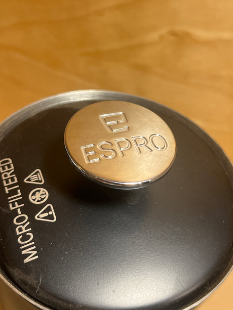 Espro French press lid with a polished metal knob, featuring the Espro logo, atop the black filter lid for micro-filtered coffee brewing.