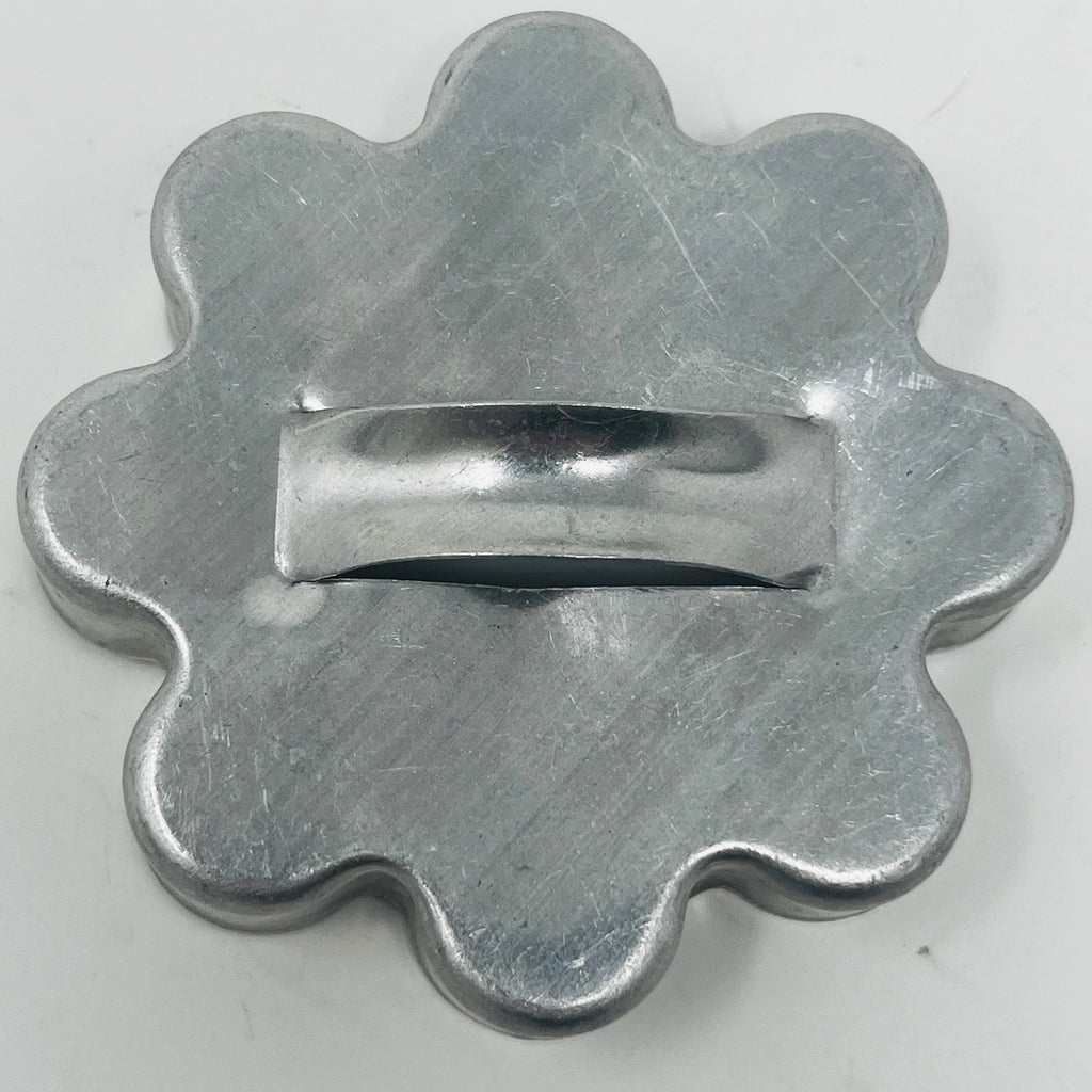 Mid century metal cookie cutter of circle with a wavy edge and handle, close-up view. From Spoons Kitchen Exchange. 