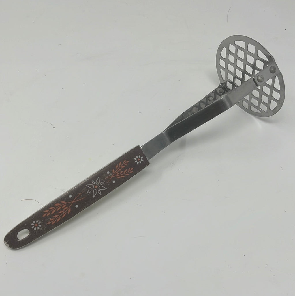 Potato masher with floral-patterned handle and metal spatula, close-up of a metal mixer, and a tool.