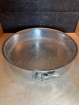 RARE Cold War springform cake pan, 12” tin made in W. Germany, with a side latch, sitting on a wooden surface. Perfect for baking larger sponge cakes.
