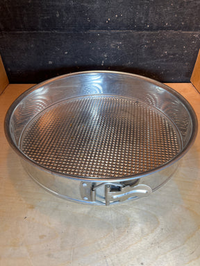 RARE Cold War springform cake pan, 12” tin made in W. Germany, with a side latch, sitting on a wooden surface. Perfect for baking larger sponge cakes.