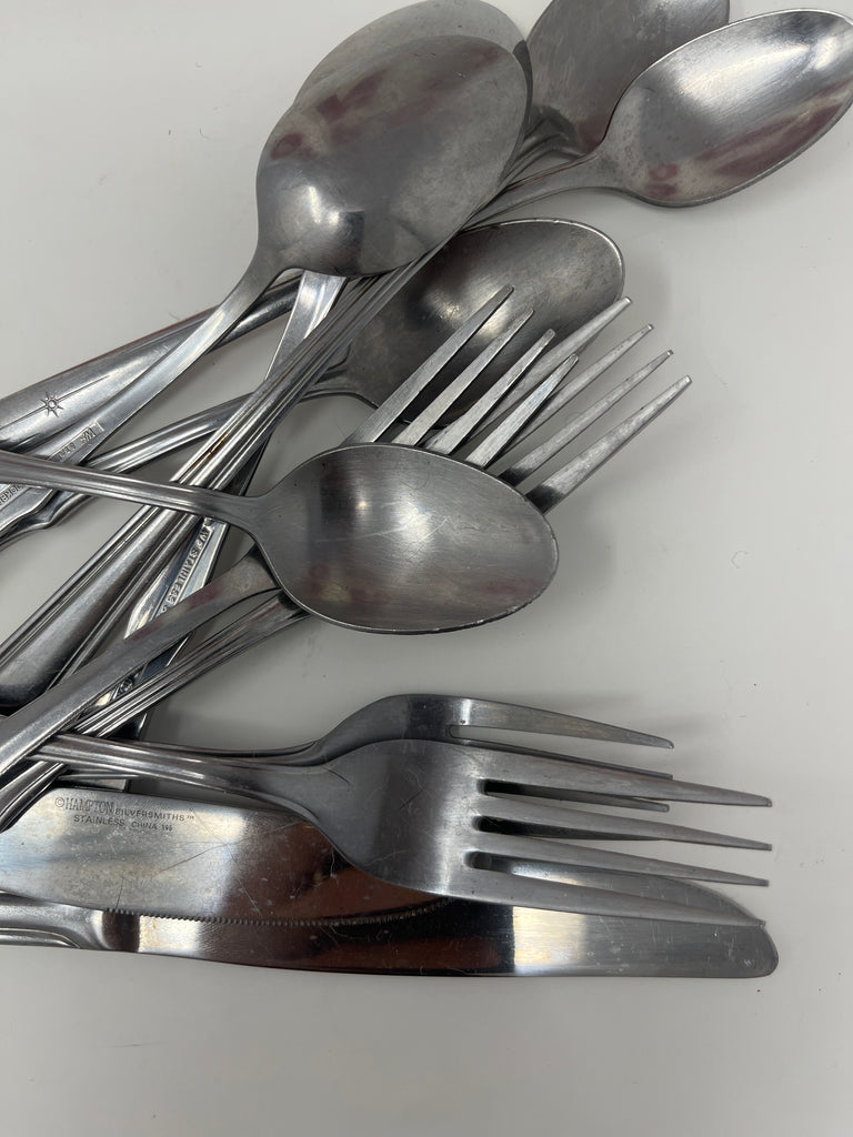 Basic metal cutlery, including forks, knives, and spoons, displayed on a white surface.