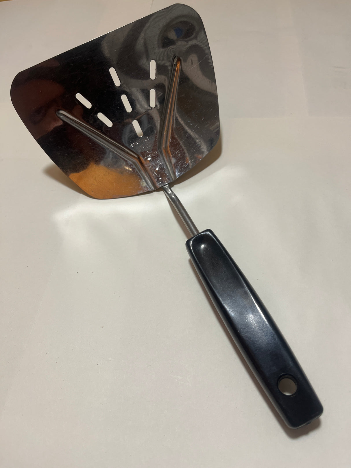 Foley Stainless Steel Wide Slotted Turner Lifter MPLS Curved Spatula with a sturdy, angled stainless-steel head and black plastic handle, ideal for flipping and lifting foods.