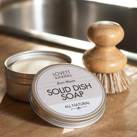Solid Dish Soap Zero Waste in a metal tin, open beside a wooden dish brush. Eco-friendly, fragrance-free soap for effective cleaning without plastic or chemicals.