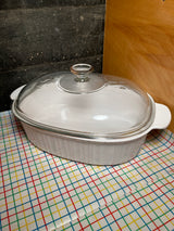 4-liter oval casserole dish with lid - PYREX Corning Ware French White F-14-B, sits tabletop, showcasing its durable ceramic build and clear glass lid, ideal for versatile cooking.