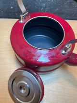 Tea kettle - steel red speckled enamelware - Paula Deen with lid beside, curved spout, and metal handles on light wood surface. Interior is dark-coated.