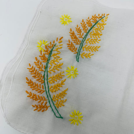 Closeup of hand-embroidered floral napkin with intricate flower and sun designs. From Spoons Kitchen Exchange. 