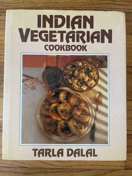 Indian Vegetarian Cookbook by Tarla Dalal, featuring colorful images of Indian dishes, including a bowl of rice with vegetables and meat, and detailed recipes.