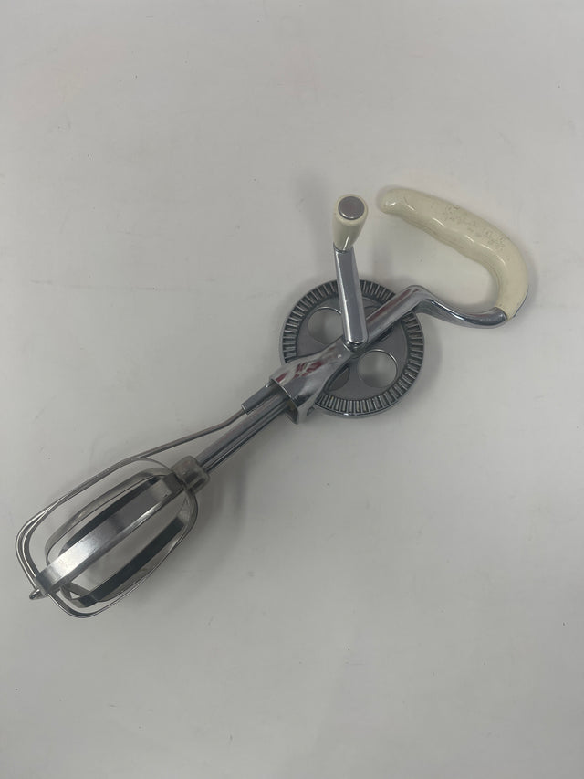 Vintage Rival handheld manual mixer model 571 with metal beaters and a white handle, designed for controlled manual mixing, perfect for enhancing baking skills.