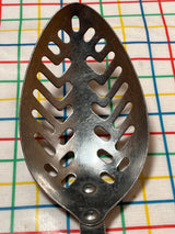 Slotted serving spoon with a perforated stainless steel bowl and black Bakelite handle, designed by EKCO Forge for efficient liquid drainage during serving.