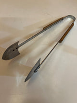 Vintage grill tongs with wood handles, featuring metal jaws shaped like paddle blades, ideal for handling coals or food on a grill.